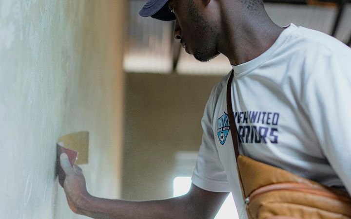 Man troweling a thin coat of compound onto a smooth wall